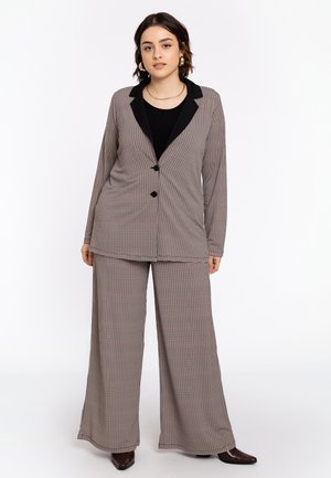 Geruit pakken in gedempte tinten met een lange blazer met zwarte revers en wijde broekspijpen, beide gemaakt van een soepele stof.