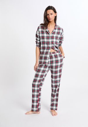 Conjunto de pijama de cuadros en gris, rojo y verde. Camisa abotonada con mangas dobladas y pantalones de pierna recta. Tela de algodón con un ajuste relajado.