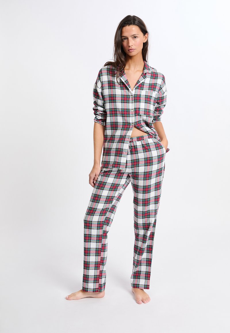 Ensemble de pyjama à carreaux en gris, rouge et vert. Chemise à boutons avec manches retroussées et pantalon droit. Tissu en coton avec une coupe décontractée.
