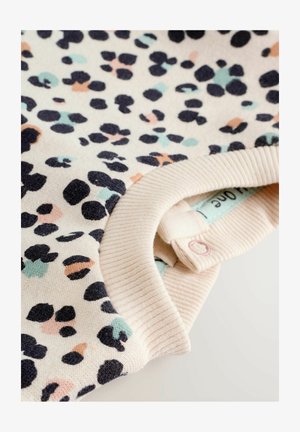 Svetlo béžový sveter s textúrovaným povrchom, s degradovaným vzorom bodiek v čiernej, mäte a broskyňovej farbe. Hladký výstrih s detailom gombíka.