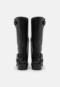Bottes noires en cuir montantes avec une texture lisse, fermeture éclair à l'arrière et boucles en argent au niveau de la cheville pour un détail supplémentaire.