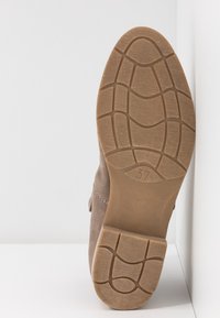 Brown suede ankle boot with a textured rubber sole featuring a grid pattern. Size 37 indicated on the sole. Side stitching visible.