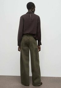 Camisa de manga larga marrón oscuro con abertura en la parte de atrás, combinada con pantalones de pierna ancha verde oliva que cuentan con bolsillos traseros y una cintura alta.