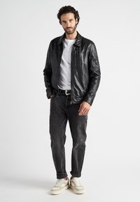 Zwarte leren jas met een kraagontwerp, ritssluiting aan de voorkant en lange mouwen. Draag het over een wit T-shirt en combineer het met donkere spijkerbroek en sneakers.