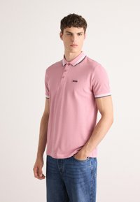 Rožinė polo marškinėliai su mezginio tekstūra, kontrastinga balta ir jūrų mėlyna dryžuota apykakle, trijų mygtukų susegimu ir juodu "BOSS" logotipu krūtinėje.