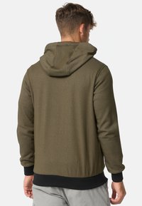 Olivenfarbener Hoodie aus weichem Stoff. Merkmale eine große Kapuze, gerippte Bündchen und einen schwarzen Bund. Glatte Textur mit subtilen Nähdetails.