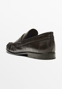 Brune læder loafers med en tekstureret overflade, rund tå og en lav, sort gummikile. Samlet detaljer langs fronten.
