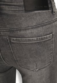Os jeans de denim cinza apresentam um bolso traseiro e um patch de couro com a inscrição "NOISY MAY". O tecido tem uma aparência suave e ligeiramente texturizada.