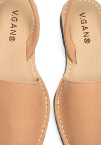 V.GAN tan vegan sandals with a smooth texture, minimalist design, open toe, and contrasting black sole, featuring visible stitching accents.