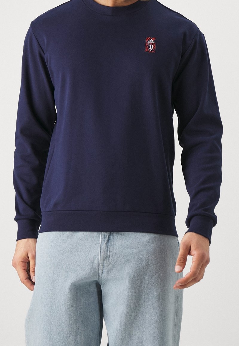 Felpa blu navy realizzata in tessuto morbido, con maniche lunghe, collo rotondo e un piccolo logo ricamato sul petto.