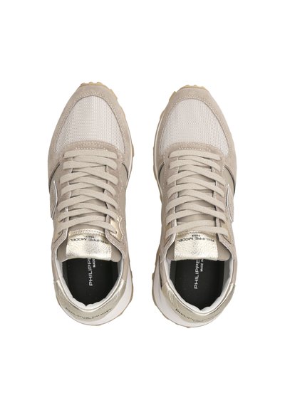 Sneaker beige con pannelli in rete e suede, dettagli metallici, lacci tondi e suola texturizzata. Logo visibile sulla soletta.