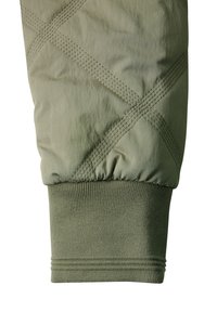 Gequilte groene stof met een geribbelde gebreide manchet, met diagonale stikpatronen en een gladde textuur. De manchet heeft meerdere gebreide details.