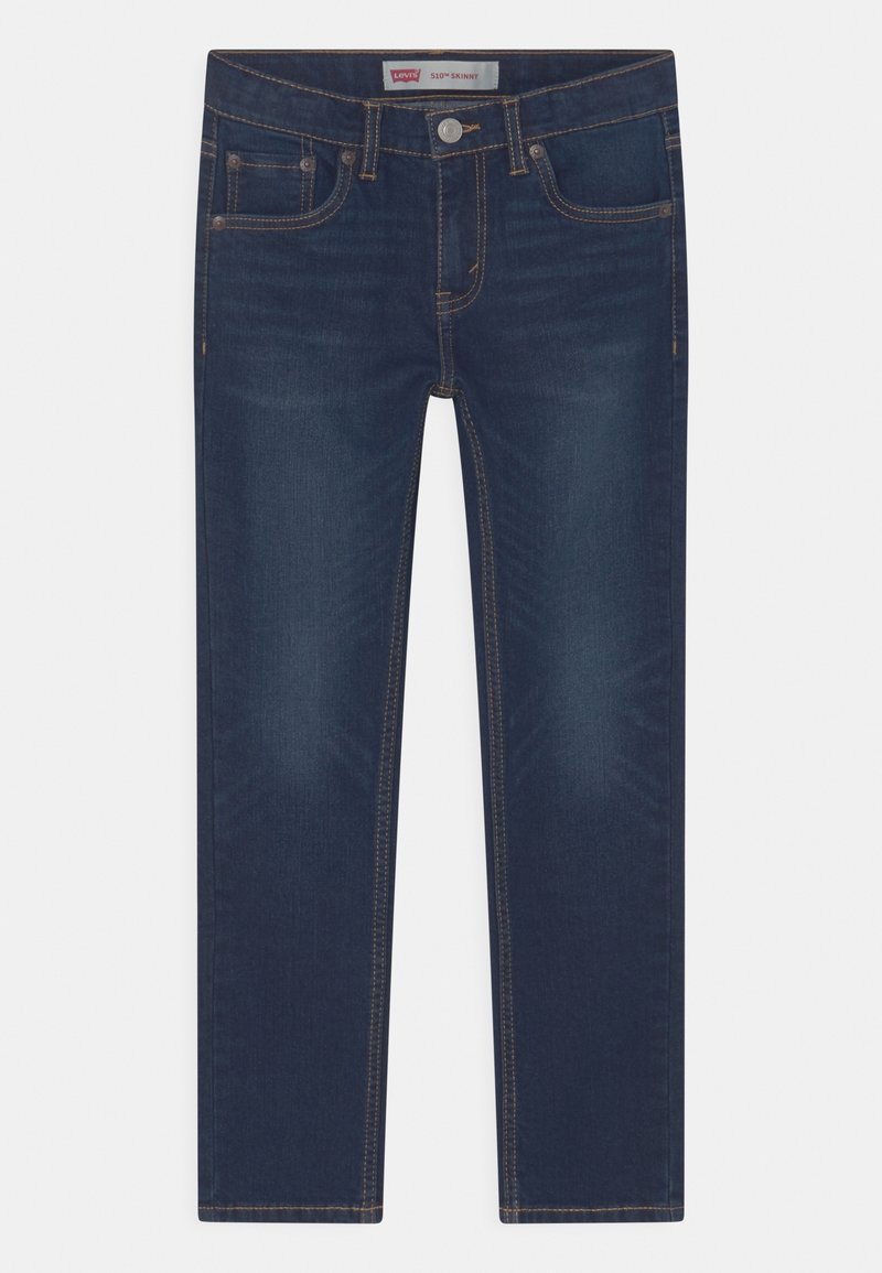 Jean skinny en denim bleu foncé avec des coutures dorées contrastantes, cinq poches et une ceinture dotée d'une fermeture à bouton et à glissière.