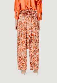 Gekleurde brede pantalons in oranje en crèmekleurig, met paisley ontwerpen, vloeiende stof en een trekkoord in de taille met plooien.
