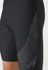 Črne kopalne hlače iz raztegljivega materiala, z oblikovano sivim valovnim vzorcem in logotipom "speedo" na strani.