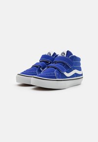 Zapatillas de lona azules con dos correas de Velcro, acentos blancos, suela de goma negra y detalles de costura blanca. Diseño de caña baja.