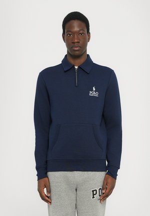 Mørkeblå genser med kvart glidelås, frontlomme og hvit "Polo Ralph Lauren" logo på venstre bryst.