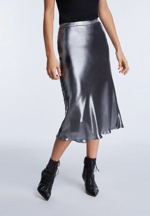 Sølvfarvet satin midi-nederdel med en glat tekstur, let glans og bølget kant, kombineret med sorte snøre-støvler til anklen.