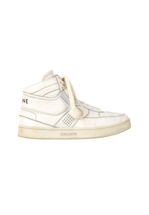 Sneakers montantes blanches avec lacets, semelle texturée, panneau latéral perforé, et marquage "CELINE" sur le talon et la semelle.