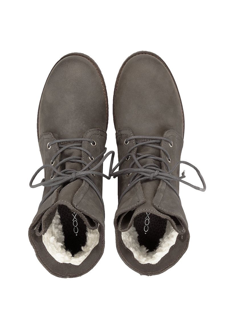 Botas de tobillo de ante gris con diseño de cordones, suave forro blanco y punta redondeada. Las suelas son oscuras y texturizadas para ofrecer agarre.
