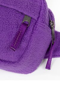 Paarse fleece tas met een gestructureerd oppervlak. Voorzien van een ritssluiting, een nylon trekker en contrasterende metalen accenten.