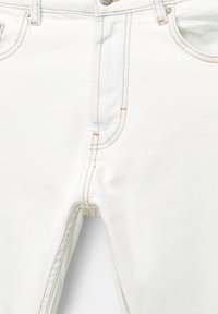 Witte denim jeans hebben contrasterende stiksels, een vijf-pocket ontwerp en een ritsluiting. De stof heeft een gladde textuur en een lichte rek.