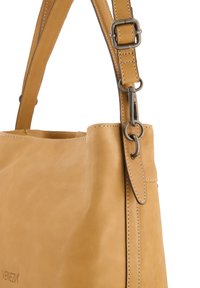 Brun læderhandbag med et elegant design, justerbar rem og metalhardware-detaljer. Har synlige sømme og en glat tekstur.