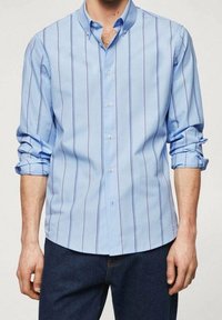 Camisa azul claro de botones con rayas verticales en azul oscuro y morado, de mangas largas arremangadas en los puños, y botones de plástico blanco.