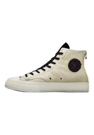 Høje sneakers i cremefarvet læder med sorte snørebånd, udstyret med en rund sort lap og en lynlås bagpå, placeret på en gennemsigtig sål.