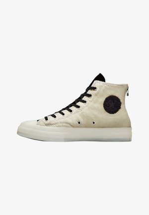 Høje sneakers i cremefarvet læder med sorte snørebånd, udstyret med en rund sort lap og en lynlås bagpå, placeret på en gennemsigtig sål.
