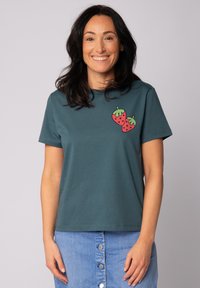 Donkerblauwe katoenen T-shirt met korte mouwen, voorzien van een graphic van twee rode aardbeien op de linkerkant van de borst. Eenvoudige ronde halslijn.