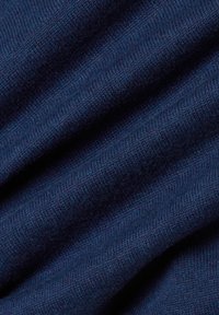 Close-up van zacht, donkerblauw gebreid stof met zichtbare fijne textuur en subtiele diagonale plooien.
