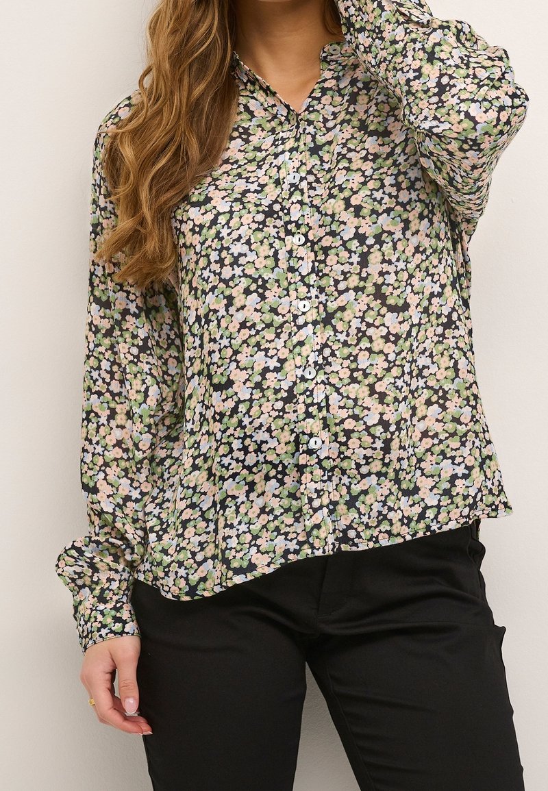 Camicia a maniche lunghe con bottoni in tessuto nero con un motivo floreale in rosa pastello, blu e verde. Caratterizzata da colletto e vestibilità comoda.