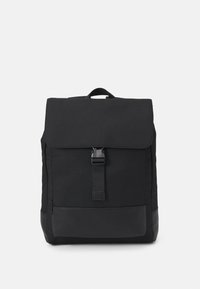 Sac à dos en tissu noir avec un rabat de fermeture, une sangle ajustable, une poche avant et un panneau inférieur en cuir noir lisse.