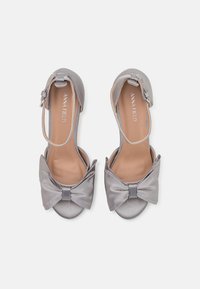 Graue Satin-Sandalen mit einer Schleifenapplikation, offener Zehe, Knöchelriemenverschluss und einem leichten Absatz. Glatte Textur und runde Form.