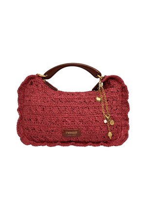 Borsa rossa intrecciata con bordi smerlati, manico in pelle marrone e tre catene di charm dorate, tra cui una conchiglia e una perla.