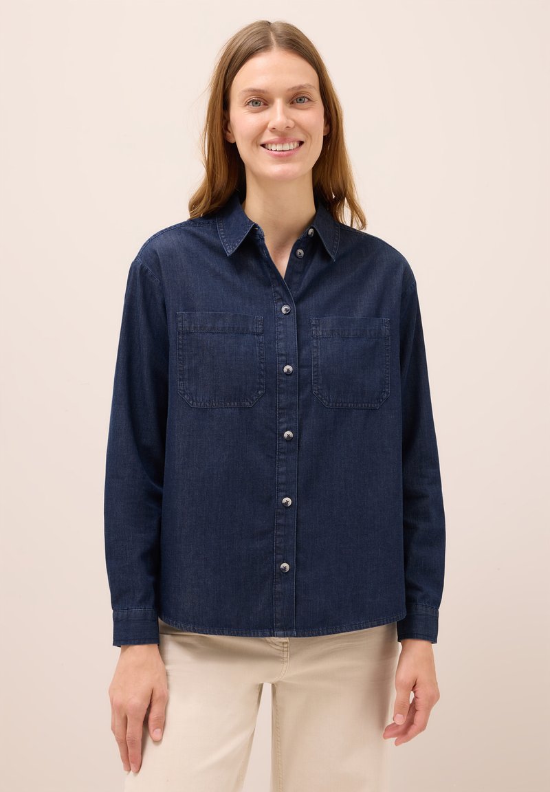 Denimskjorta i mörkblått, med knappstängning fram, två bröstfickor och långa ärmar. Mjuk textur med en avslappnad passform.