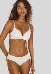 Balts bezšuvju krūšturis un peldbikses komplekts ar v veida dekoltē dizainu, ar ziedu akcentu izšuvumu, regulējamām siksnām un mīkstu tekstūru.