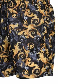 Shorts de bain avec un fond noir arborant un motif orné doré et bleu éclatant. Taille élastique avec détail à cordon.