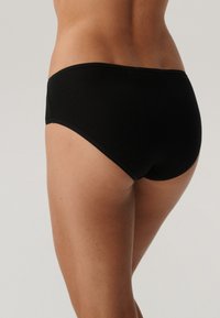 Czarne bawełniane majtki typu hipster z gładkim, bezszwowym wykończeniem i niskim stanem. Materiał ma delikatny połysk i miękką teksturę.