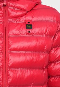 Red padded jacket with horizontal quilting, zipper closure, and a small black and yellow "Blauer U.S.A." logo patch on the chest.