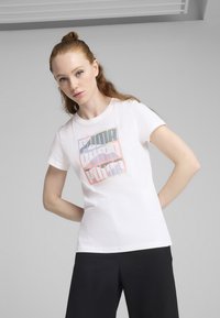 Bílý bavlněný tričko s multicolor grafickým designem, na kterém je výrazně zobrazeno slovo "PUMA" v tučných, vrstvených písmenech. Krátké rukávy.