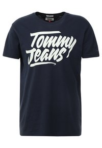 Mörkblå bomull T-shirt med fet vit "Tommy Jeans" text på framsidan, rund halsringning, korta ärmar och avslappnad passform.