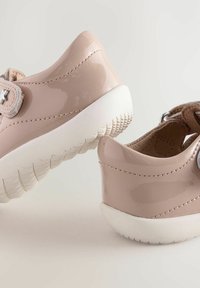 Rosa Lacklederschuhe mit einer weißen Sohle, ausgestattet mit einem Klettverschluss und strukturierten Akzenten. Abgerundetes Design und leicht erhöhter Absatz.