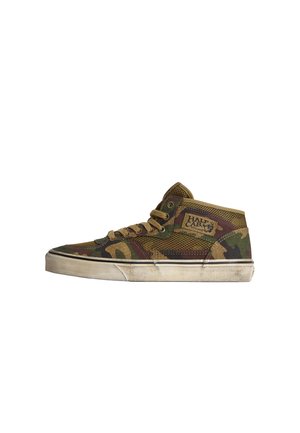 Mid-Top Sneaker mit grünem, braunem und schwarzem Camouflage-Muster, Mesh-Gewebe, beigen Schnürsenkeln, „Half Cab“-Patch an der Seite und abgenutzter weißer Gummisohle.