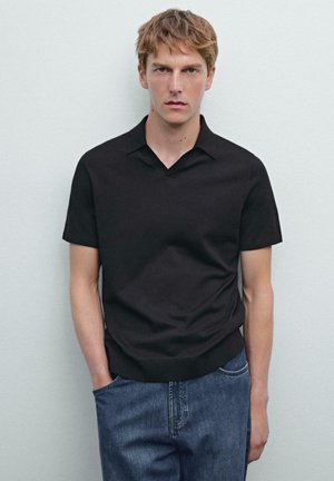 Černá polokošile s krátkým rukávem a véčkovým výstřihem, hladká textura a jednobarevný design, v kombinaci s světlými modrými džíny.
