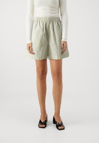 Light green striped shorts with an elastic waistband, featuring a relaxed fit and smooth, lightweight fabric. Accompanied by black heeled sandals.