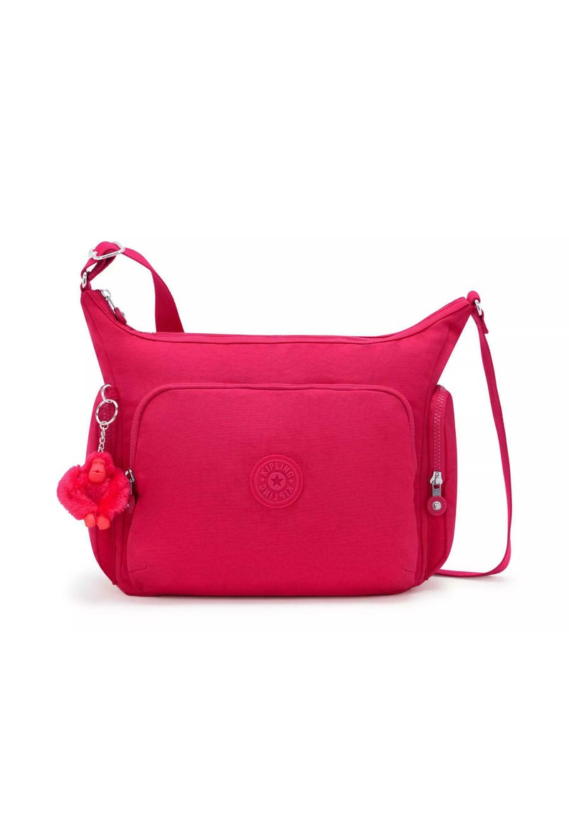 Rosa tygcrossbody-väska med texturerad yta, dragkedjestängning, framficka och en nyckelring i form av en apa. Har en justerbar rem.