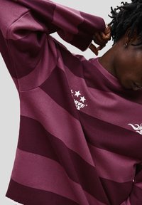 Violet striped sweatshirt with a crew neckline. Features a textured fabric, ribbed cuffs, and white logo with five stars on the chest.