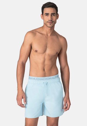 Lichtblauwe zwembroek met een elastische tailleband, voorzien van het merklogo "MUCHACHO", een trekkoord en een gladde, lichte textuur.